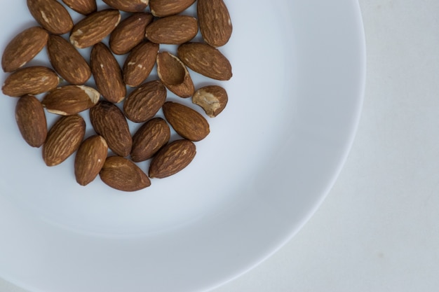 Circle shape Group middle Almond on white dish top left closeup top view