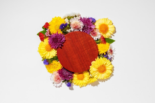 Circle wooden board surrounded with flower buds on gray