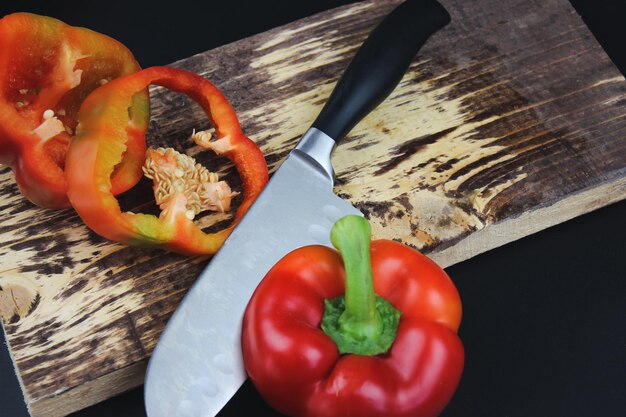 Circles of red pepper on a cutting board High Angle View Of pepper Slices With Knife On Cutting Board On Dark Background