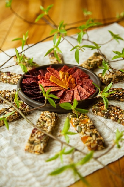 A circular composition on the table with homemade fruit leather pieces in the bowl and granola bars