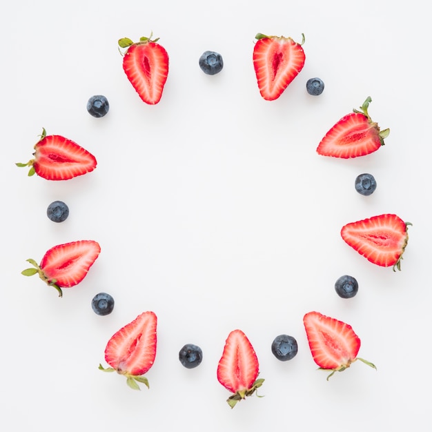 Circular frame made with halved strawberries and blueberries isolated on white background