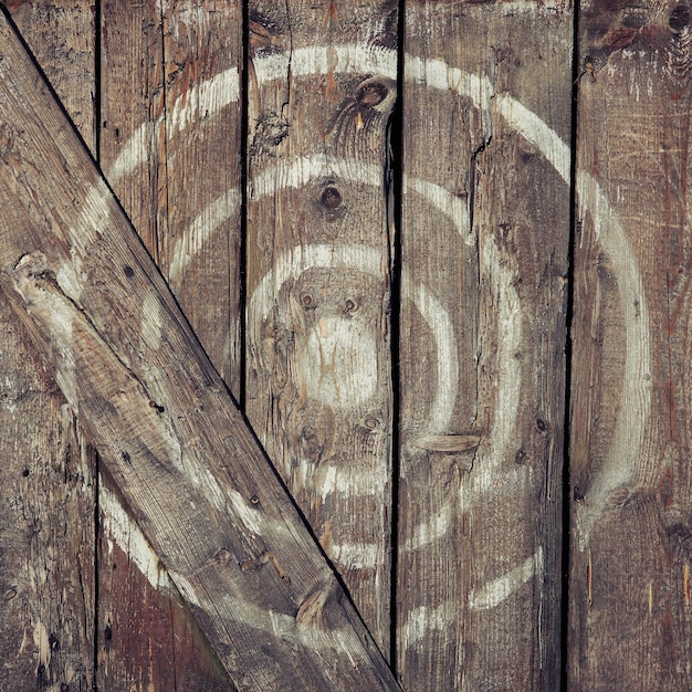Круглая мишень нарисована белой краской на деревянной двери