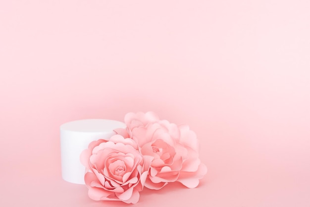 Circular white platform for product presentation with roses on pink background Copy space