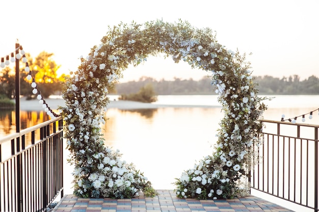 Cirkel huwelijksboog versierd met witte bloemen en groen buitenshuis