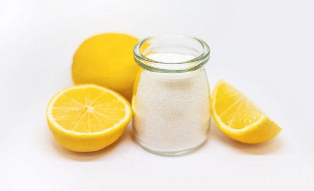 Лимонная кислота в стеклянной банке и лимоны