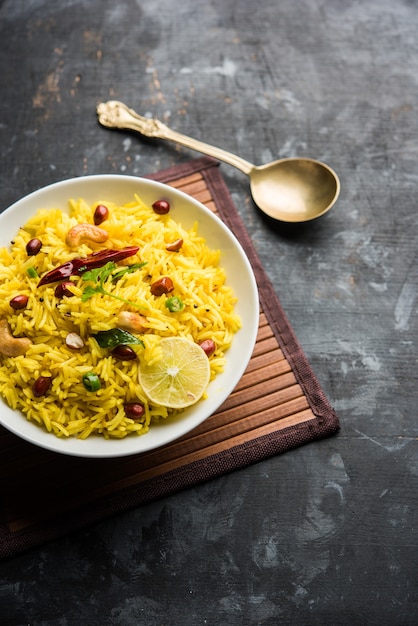 Citroenrijst of fodnicha bhat is Zuid-Indiase kurkuma rijst of maharashtrian recept met overgebleven rijst gegarneerd met noten curry bladeren en citroensap, selectieve focus