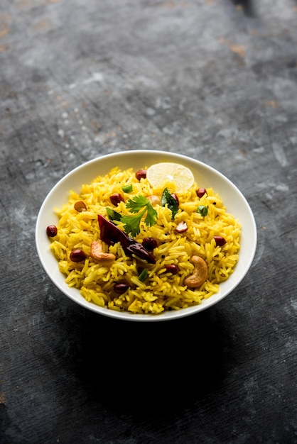 Citroenrijst of fodnicha bhat is zuid-indiase kurkuma rijst of maharashtrian recept met overgebleven rijst gegarneerd met noten curry bladeren en citroensap, selectieve focus