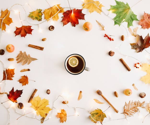 Citroenthee in een frame gemaakt van herfstbladeren op witte achtergrond Flatlay bovenaanzicht kopieerruimte