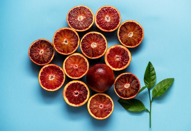 Citrus background pattern with red oranges and green leaves on a blue background Flat lay