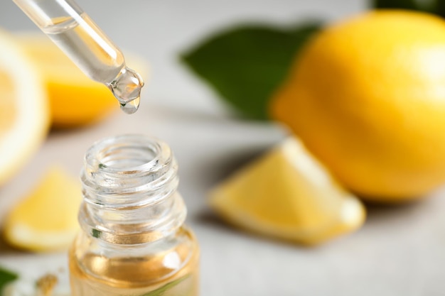 Citrus essential oil dripping from pipette into bottle closeup Space for text