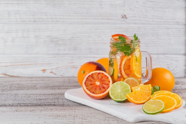 Citrus fruit and herbs water for detox or dieting in glass bottles on wooden board