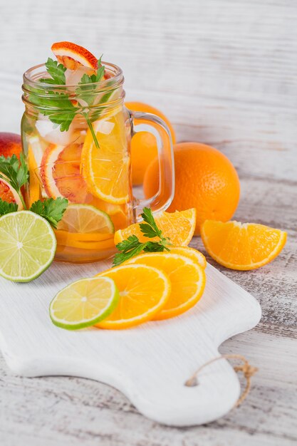 Citrus fruit and herbs water for detox or dieting in glass bottles on wooden board