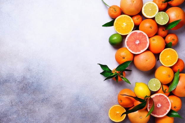 Цитрусовые. Ассорти из свежих цитрусовых с листьями. Апельсин, грейпфрут, лимон, лайм, мандарин. Вид сверху