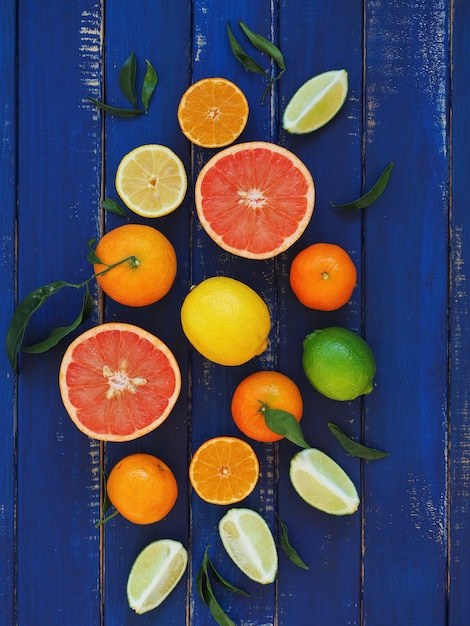 Citrus fruits on blue wooden surface - oranges, lemons, lime, mandarines and grapefruit