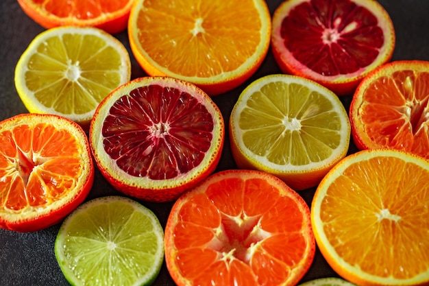 Citrus fruits cut in half oranges tangerines yellow lemons green limes closeup selective focus