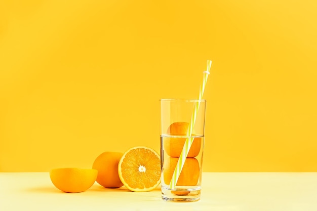 写真 黄色の背景に水とガラスを通してゆがんだ柑橘系の果物