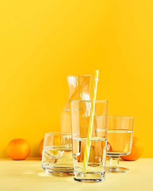 Photo citrus fruits distorted through water and glass on yellow background