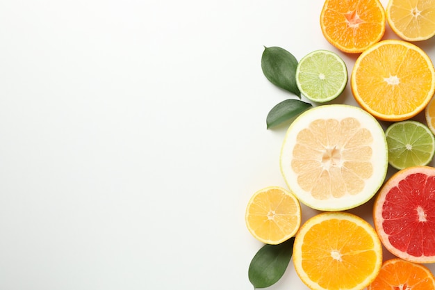 Citrus fruits and leaves on white background, space for text