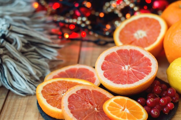 Citrus fruits and red currant on wooden table.