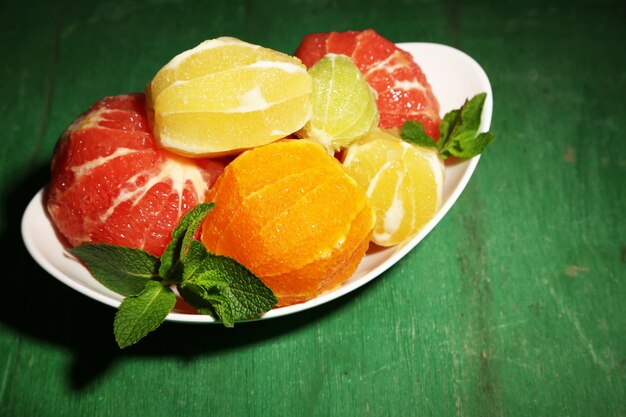 Citrus fruits without skin, on plate, on wooden background