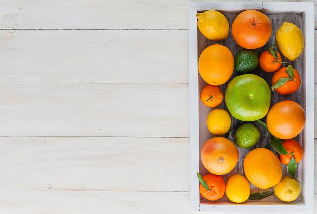 Citrus fruits in a wooden box on a light wooden background