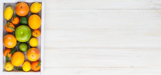 Citrus fruits in a wooden box on a light wooden background