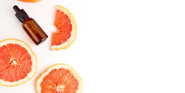 Citrus or grapefruit essential oil in glass bottle with fresh grapefruit on white background. Spa and skincare product