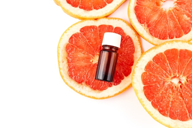 Citrus or grapefruit essential oil in glass bottle with fresh grapefruit on white surface