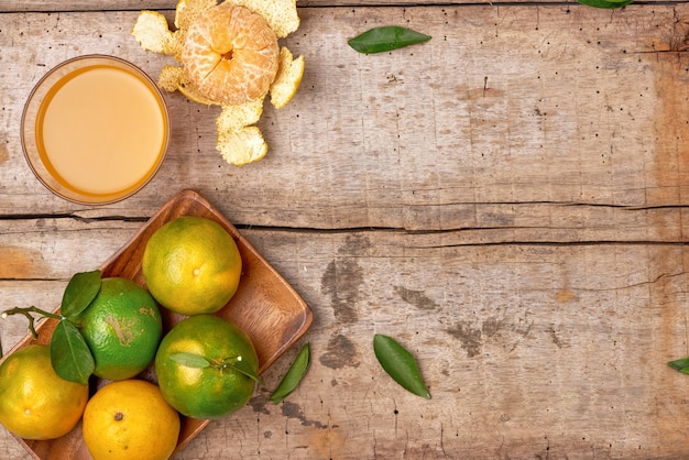 Citrus juice in glass and fresh mandarin orange on wooden background