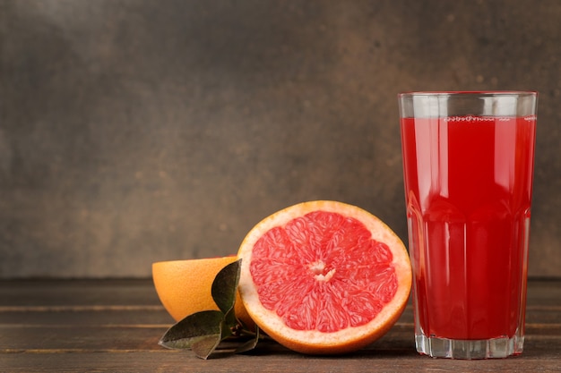 Citrus juices. grapefruit juice in a glass with fresh fruit on a brown wooden table