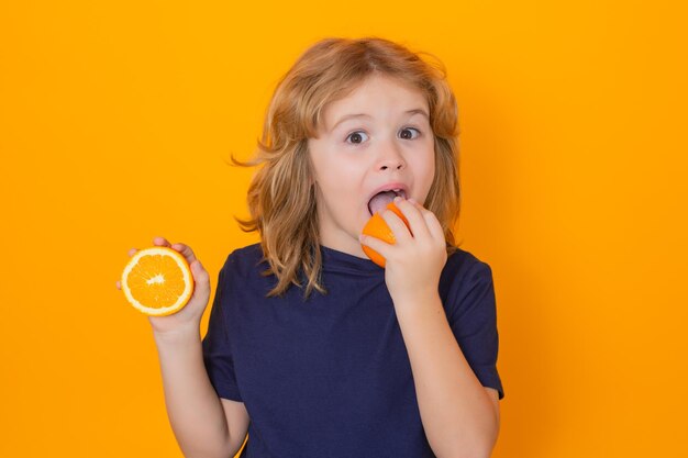 Photo citrus kid eat orange in studio studio portrait of cute child lick orange isolated on yellow background