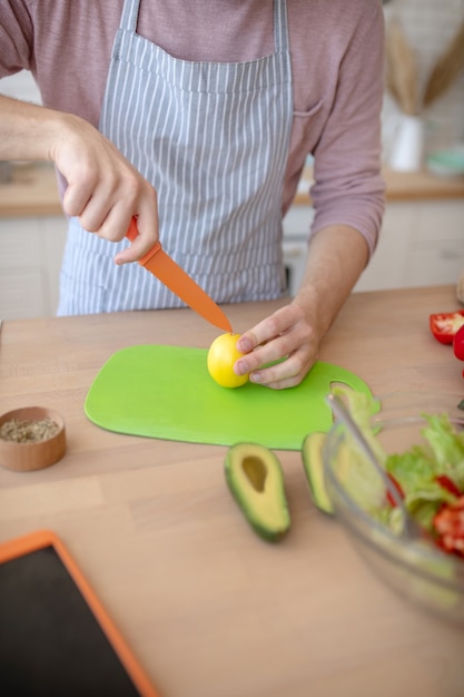 Citrus. A man chopping a lemon with a knife while cooking