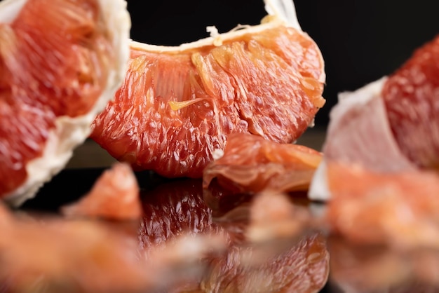 citrus op de zwarte spiegel geschild citrus grapefruit met rood vlees de vrucht wordt weerspiegeld op een zwart oppervlak zijbeeld