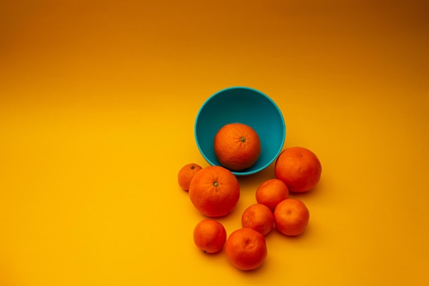 Citrus oranges in a bowl on a yellow background