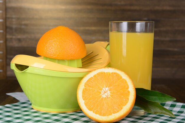 Citrus press and oranges on table on wooden background