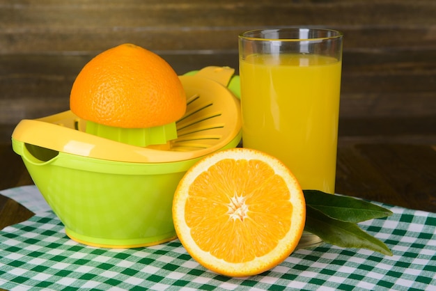 Citrus press and oranges on table on wooden background