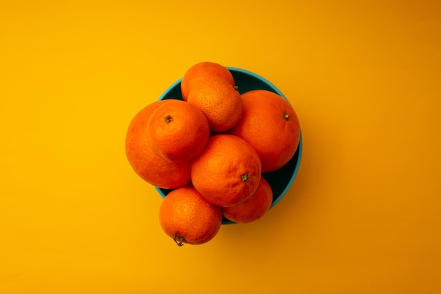 Citrus sinaasappelen in een kom op een gele achtergrond