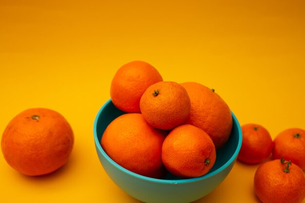 Citrus sinaasappelen in een kom op een gele achtergrond