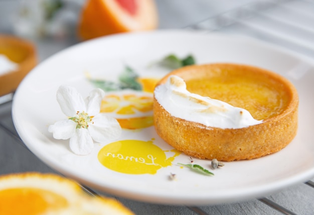 Citrus taartje op het witte bord versierd met geschilderde citroen en witte bloem erop