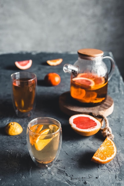 Photo citrus tea in a transparent teapot on a gray concrete background. healthy drink, vegan, eco product.