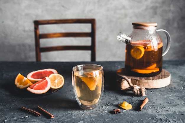 Citrus tea in a transparent teapot on a gray concrete.