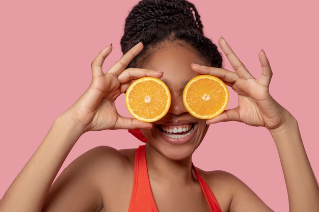 Citrus. Young african american woman with slices of orange in hands