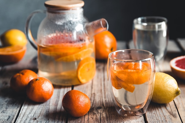 Citrusthee in een transparante theepot op een tafel met grapefruit en op een houten tafel. Gezond drankje.