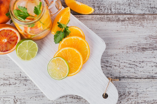 Foto citrusvruchten en kruidenwater voor detox of dieet in glazen flessen op een houten bord