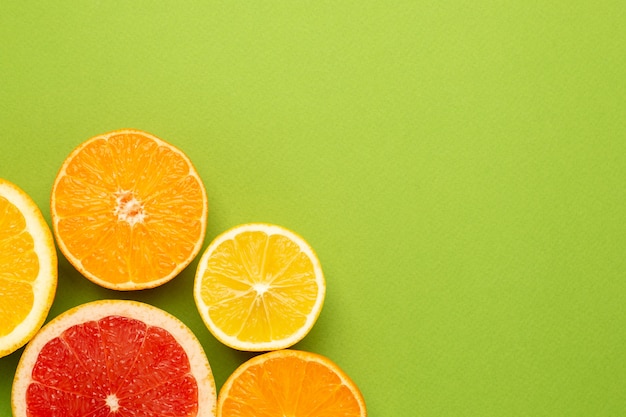 Citrusvruchten op groene achtergrond met flatlay fruit, copyspace, de zomer minimale samenstelling met grapefruit, citroen, mandarijn en sinaasappel