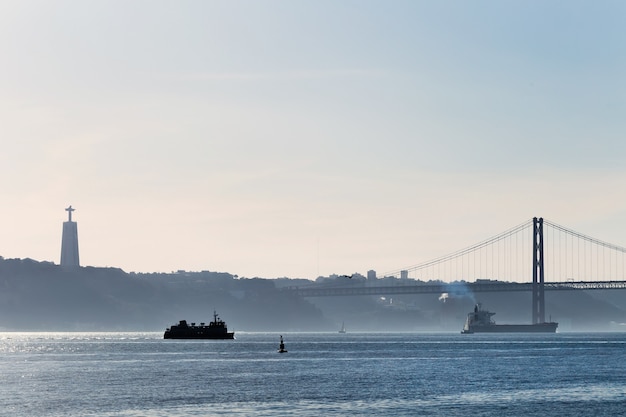 A city on the banks of the river Tagus and silhouette of the monument.