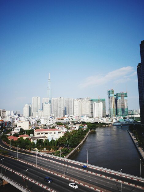 City by river and buildings against blue sky