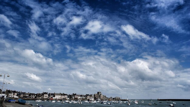 City by sea against cloudy sky