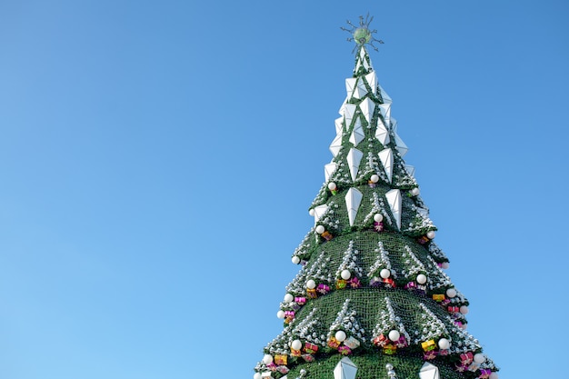 青い空を背景に市のクリスマスツリー。クリスマスの花輪。週末と祝日