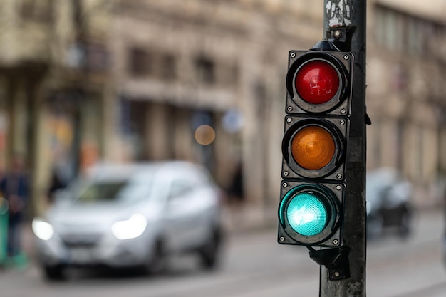 a city crossing with a semaphore on blurred background with cars in the evening streets green light
